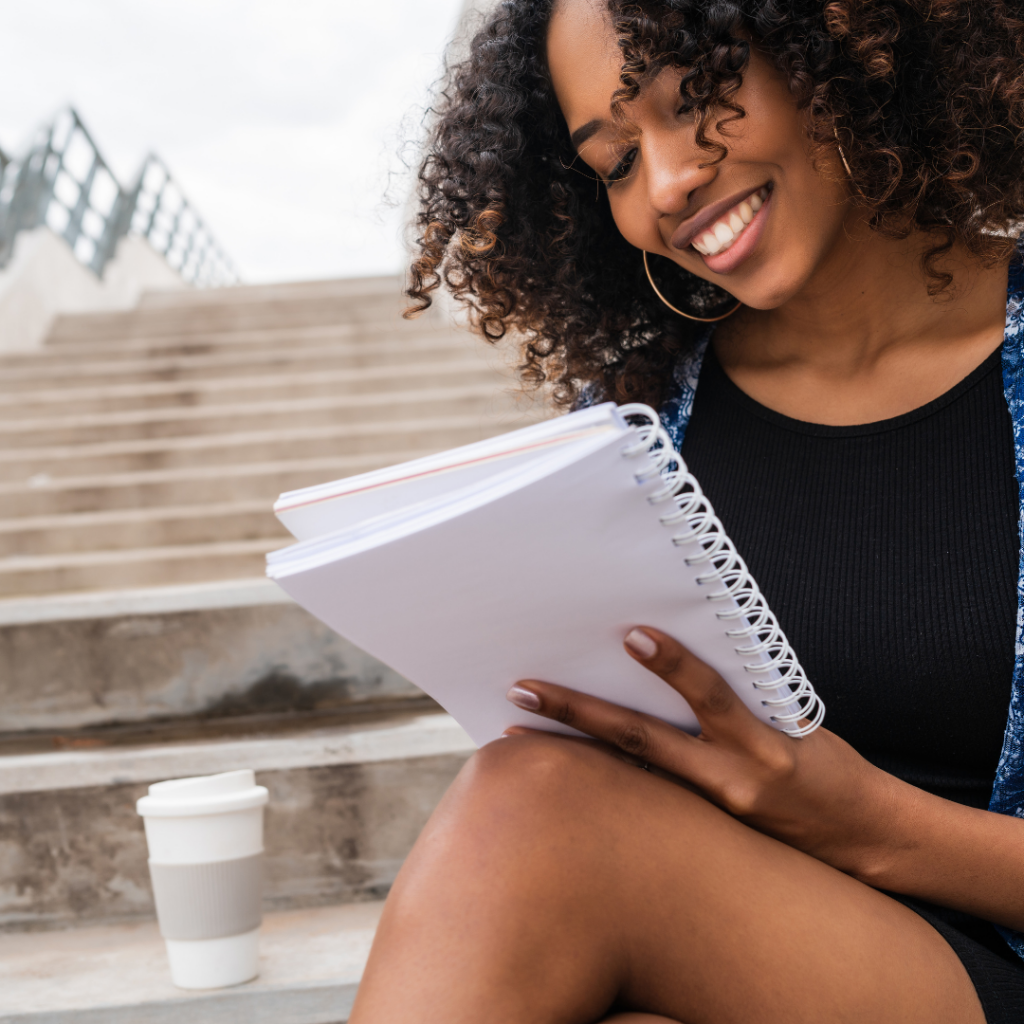 Women Sitting Outside on Steps and Writing in a Notebook