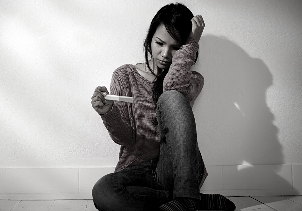 Photograph of Woman Sitting on the Ground Looking At a Pregnancy Test